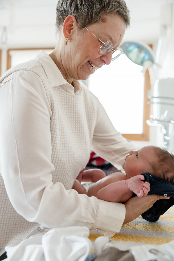 Hebamme hält Neugeborenes fest.