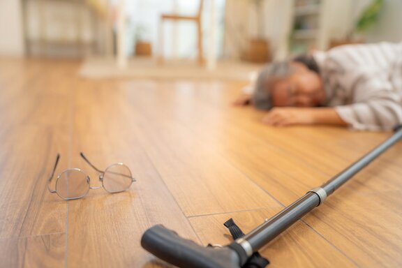 Ältere Frau ist beim Staubsaugen gefallen und liegt auf dem Boden 