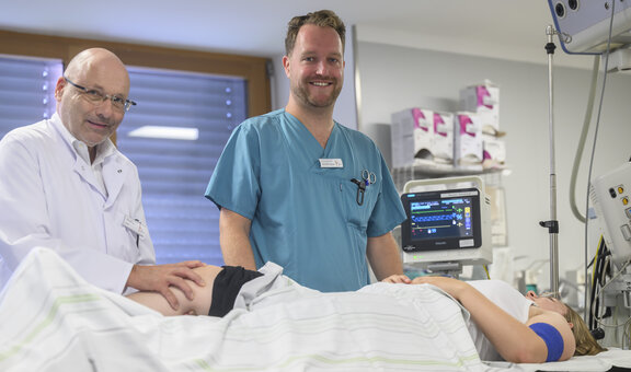 Dr. med. Alexander Joist und eine ZNA Fachkraft behandeln eine Person am Bein, indem Dr. Alexander Joist das Bein leicht bewegt.