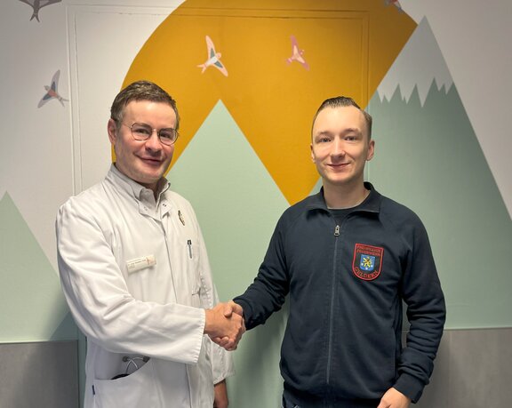 Chefarzt dankt Mitarbeiter der freiwilligen Feuerwehr nach Spende. 