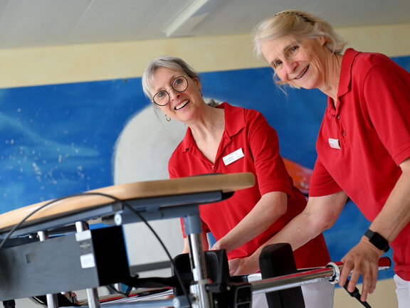 Ergotherapeutinnen schauen in die Kamera und lächeln während Sie eine Gangtherapie vorbereiten 