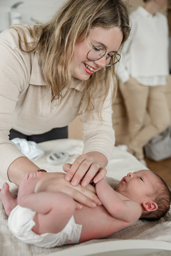 Hebamme hält Neugeborenes fest.