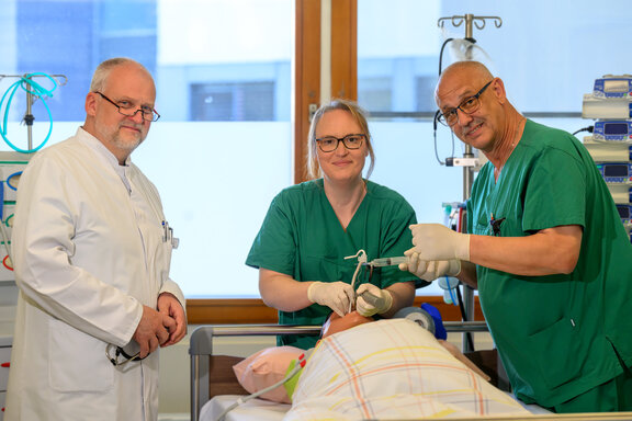 Arzt und Mitarbeiter stehen an einem Krankenbett mit Beatmungsgerät