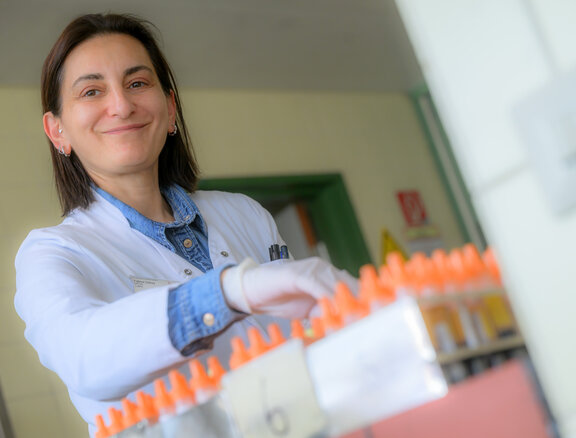 Labormitarbeiterin sortiert Proben in einem Reagenzglas ein.