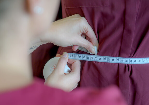 Mitarbeiterin im Lipödem Department misst den Bauchumfang einer Patientin mit einem Maßband. 
